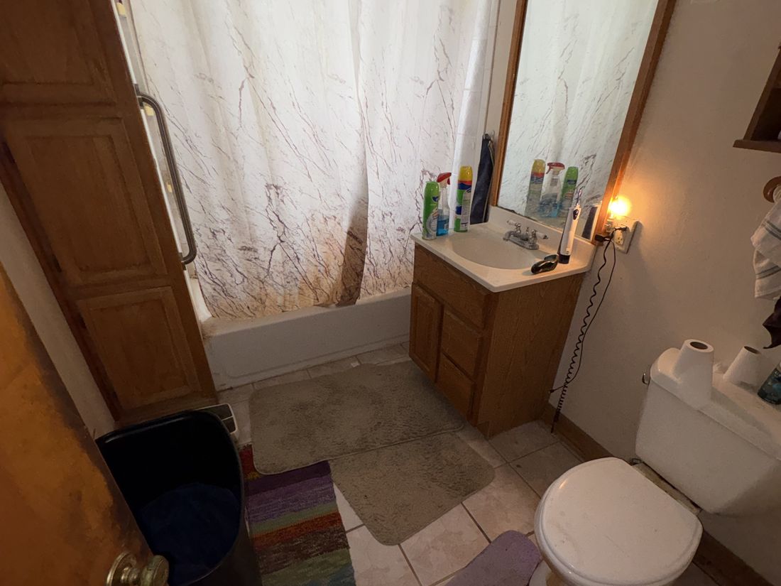 Original bathroom with dated wood vanity in the West Allis, Wisconsin duplex