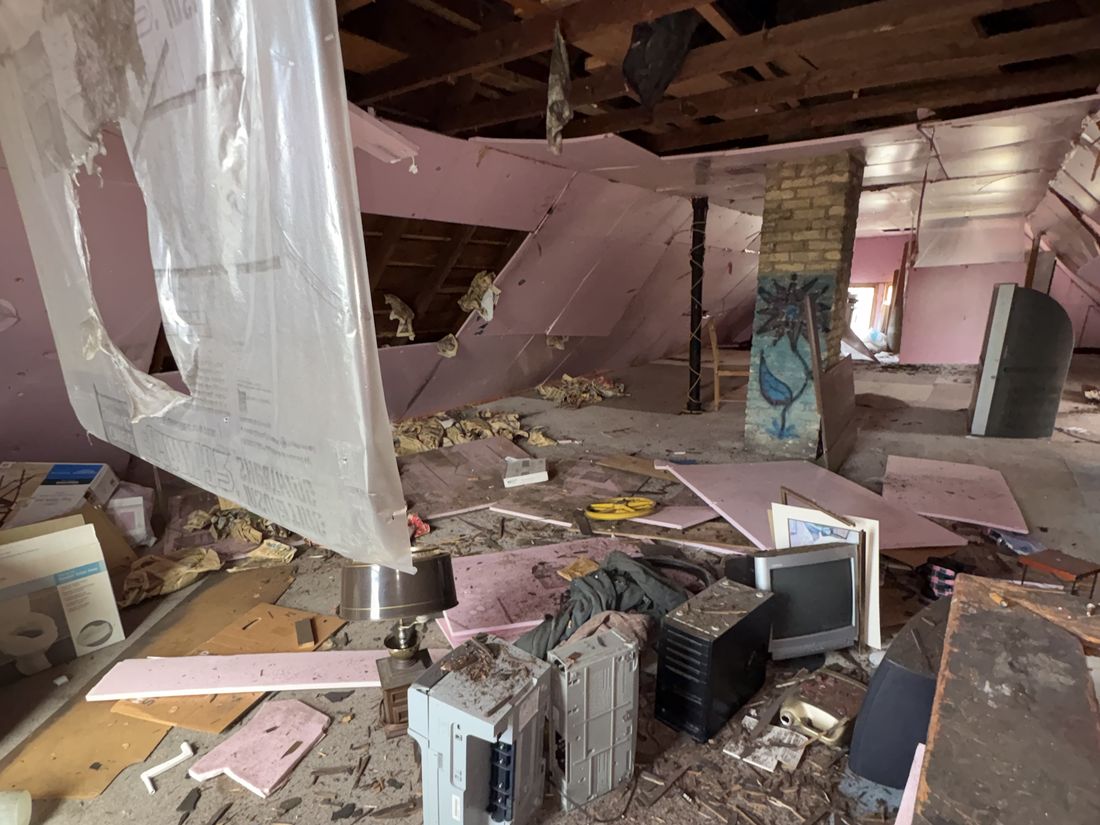 Water-damaged room with fallen ceiling material and debris in the West Allis duplex